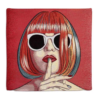 Ein dekoratives Kissen mit der Abbildung einer Frau mit rotem Bob-Haarschnitt, die eine große weiße Sonnenbrille und roten Lippenstift trägt und ihren Finger in einer „Pst“-Geste auf ihre Lippen legt, auf rotem Hintergrund.