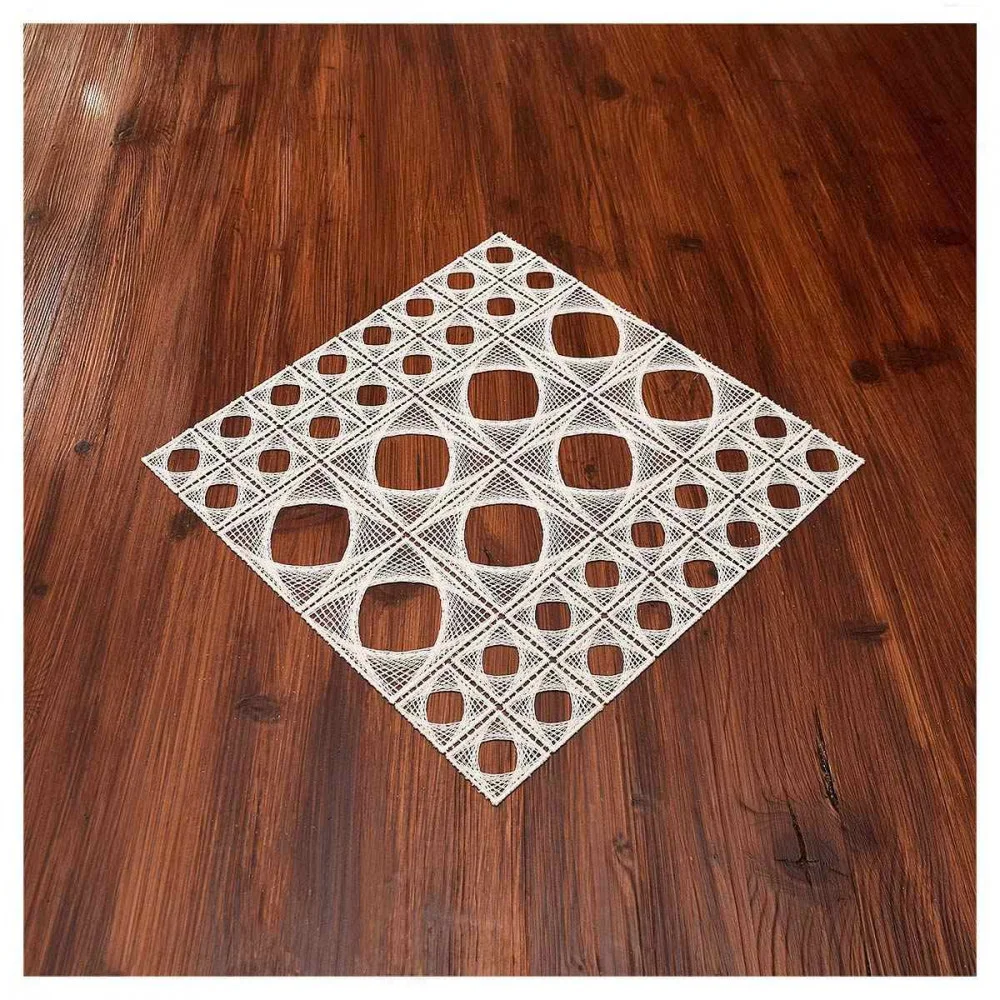 Ein gitterartiges, geometrisches Deckchen mit quadratischen und rautenförmigen Ausschnitten ist auf einem polierten Holztisch platziert, wodurch ein auffälliger Musterkontrast zwischen dem weißen Kunstwerk und dem dunklen Holz entsteht.