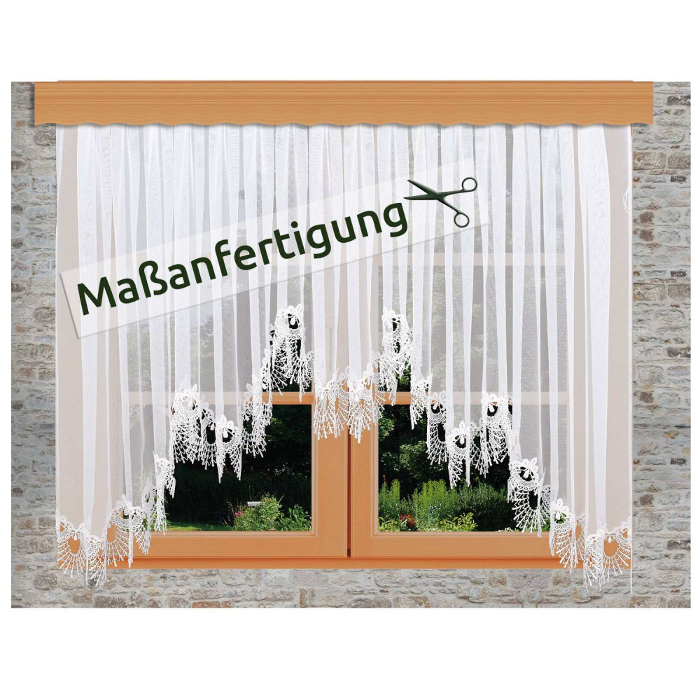 Weißer Spitzenvorhang Nastja mit floralen Mustern, der an einem Holzfenster in einer Steinwand hängt. Ein Schild mit Scherensymbol und dem deutschen Text "Maßanfertigung" ist über den Vorhang gelegt.