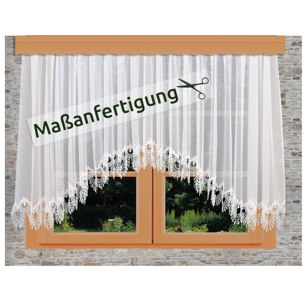 Weißer Spitzenvorhang mit floralen Mustern, der an einem Holzfenster in einer Steinwand hängt. Ein Schild mit Scherensymbol und dem deutschen Text "Maßanfertigung" ist über den Vorhang gelegt.