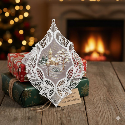 Eine Weihnachtsdekoration aus Spitze im Stil der Plauener Spitze, die eine verschneite Dorfszene zeigt, steht auf eingepackten Geschenken. Ein geschmückter Baum, ein glühender Kamin und ein Geschenkanhänger mit deutschen Weihnachtsgrüßen vervollständigen dieses festliche Fensterbild.