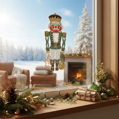 Ein festliches Fensterbild Nussknacker hängt am Fenster mit einer verschneiten Winterszene draußen. Drinnen herrscht wohlige Wärme mit einem Kamin, eingepackten Geschenken, Tannenzapfen und Grünzeug - eine zauberhafte Weihnachtsdekoration auf der hölzernen Fensterbank.