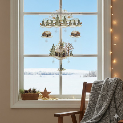 Ein gemütliches Zimmer mit einem Holzstuhl, der in eine graue Strickdecke gehüllt ist, sitzt an einem Fenster, das mit Adventsdeko geschmückt ist, darunter eine Fensterbild-Kirche und festliche Hängeornamente, und blickt auf eine verschneite Landschaft unter einem klaren blauen Himmel.