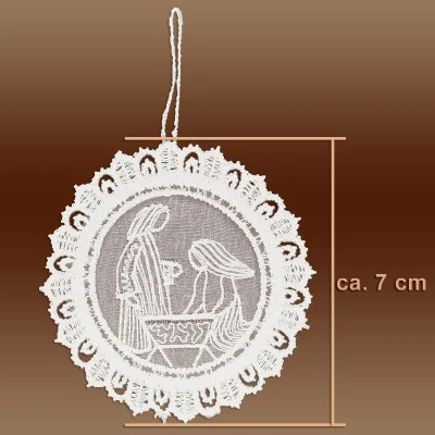 Ein kreisförmiges weißes Spitzenornament aus Plauener Spitze mit einem Krippenmotiv in der Mitte, Spitzenbordüren und einer Aufhängeschlaufe. Perfekt als Adventsbaumbehang, er misst ca. 7 cm im Durchmesser. Der Hintergrund ist braun.