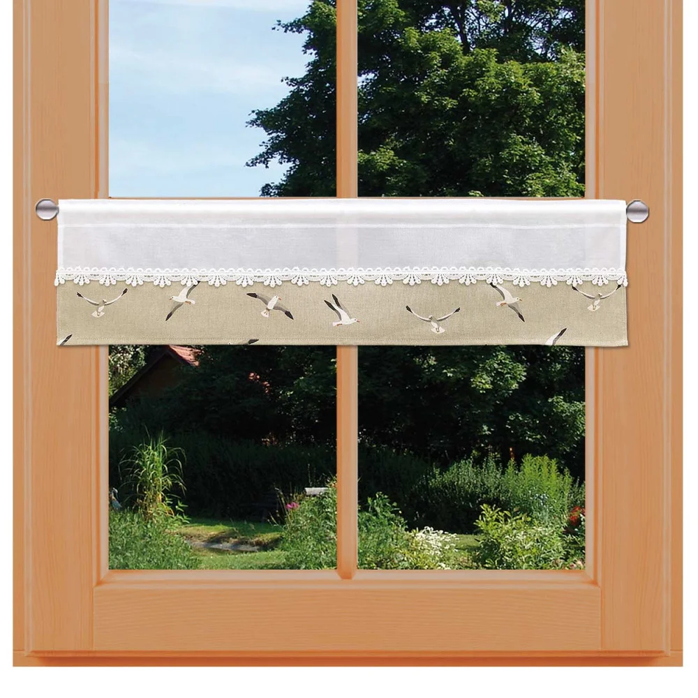 Ein holzgerahmtes Fenster mit einem kurzen beige-weißen Vorhang mit Spitzenbesatz, der ein Muster aus fliegenden Vögeln zeigt. Durch das Fenster sind grüne Bäume, Gras, Sträucher und ein Teil eines Gartens oder Hauses im Hintergrund zu sehen. Höhe 20 cm